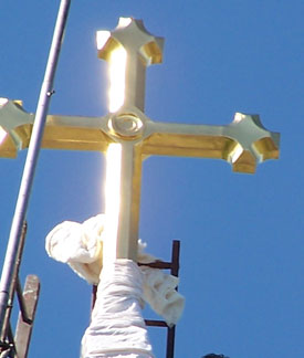 Gilded cross being re-installed on a steeple